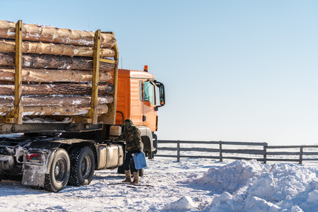 Trees truck transportation parked on snow, with driver add fuel in winterの写真素材