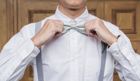 Close-up young Asian man in white shirt holding bow tieの写真素材