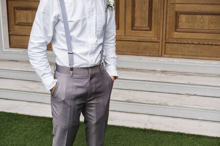 Close-up young man in white shirt and gray slag trouser, with hand in the pocketの写真素材