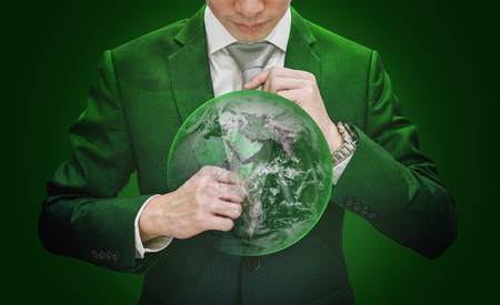 Businessman in green suit holding necktie with green globe, on green background. Element of this image are furnished by NASAの写真素材
