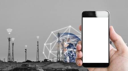 Hand holding mobile smartphone empty white screen, and telecommunication towers with wifi signal signs with global network connection.の写真素材