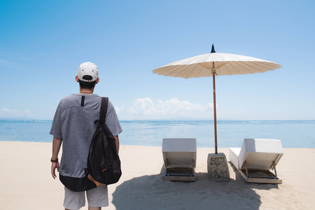 a man with backpack standing on the beach in summer. Vacation travelling in summer and summer recreation pursuit conceptの写真素材