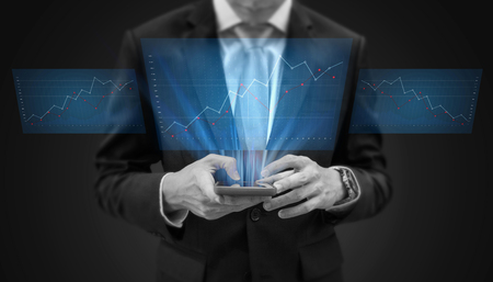 Businessman using mobile phone and futuristic raising graph hologram screenの写真素材