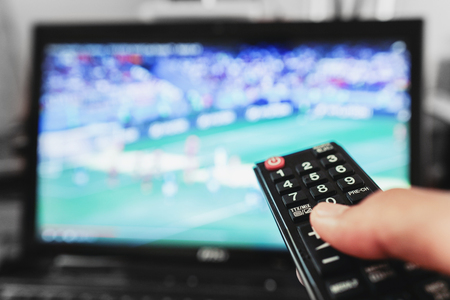 Watching tv, football match, movie and etc. Hand using remote controlの写真素材