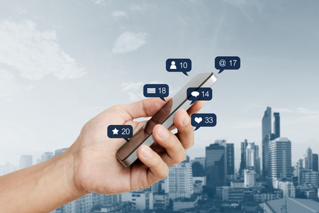 Hand holding mobile smart phone, with social media and social network notification iconの写真素材