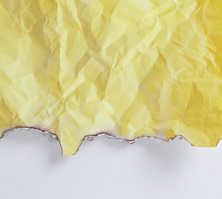 Burned yellow crumpled paper on white backgroundの写真素材