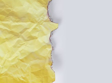 Burned yellow crumpled paper on white backgroundの写真素材