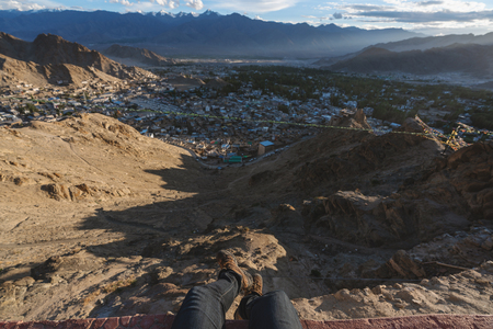 Travelling in Leh city, in Ladakh, India. a man sitting on cliff enjoying leh city view in the morningの写真素材