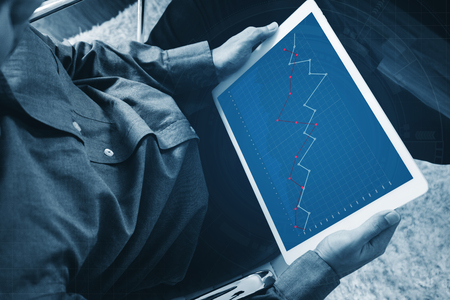 a man working on digital tablet, business decreasing graph on screenの写真素材