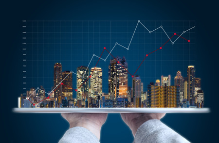 Real estate business investment and building technology. Hand holding digital tablet with buildings...