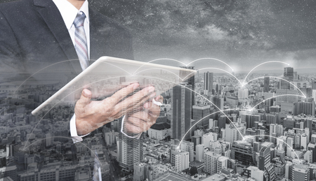 Double exposure businessman using digital tablet, and cityscape. Business network, blockchain technology and internet connectionの写真素材