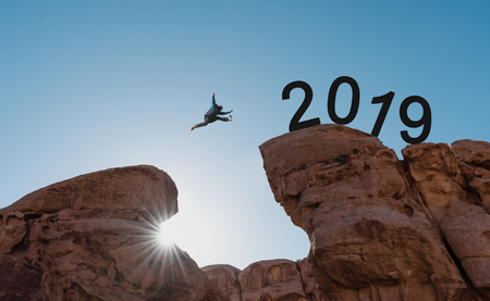 New year concept, silhouette a man jumping across cliff to 2019の写真素材