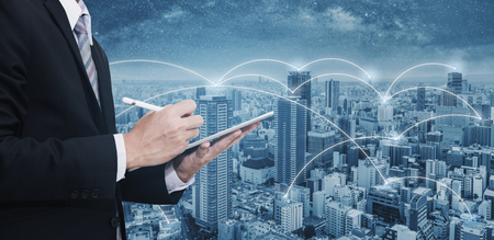 Double exposure businessman using digital tablet, and cityscape. Business network, blockchain technology and internet connectionの写真素材