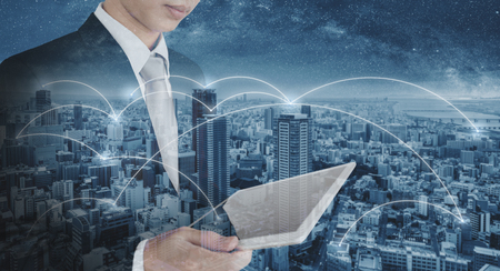 Double exposure businessman using digital tablet, and cityscape. Business network, blockchain technology and internet connectionの写真素材
