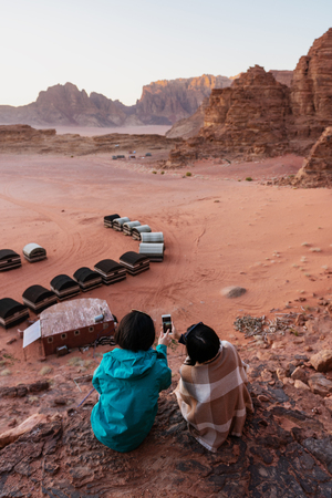 Travelling in Wadi Rum desert, Jordan. Taking photo by smartphone on cliffの写真素材