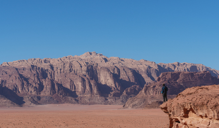 Traveler standing on edge of mountain cliff, at Wadi Rum desert in Jordan. Travel lifestyle and adventure and journeyの写真素材
