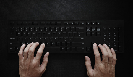 Top view, Hand typing computer keyboard on black background