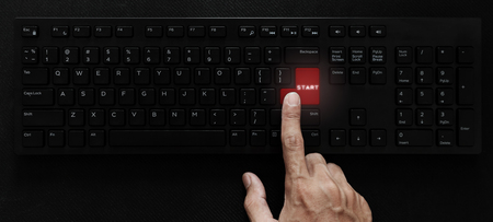 Hand pressing start button on computer keyboard