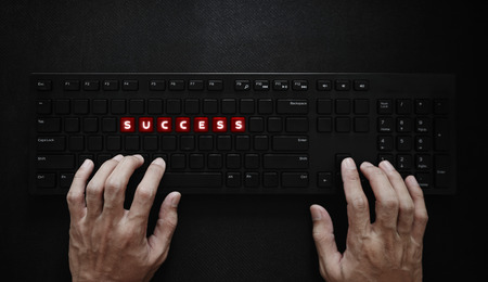 Success concept. Hand typing on computer keyboard and SUCCESS on red buttonsの写真素材