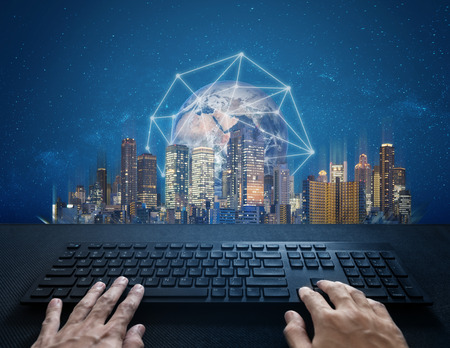 Internet, digital networking and connection. Hand typing computer keyboard and global network connection and the city. Element of this image are furnished by NASAの写真素材