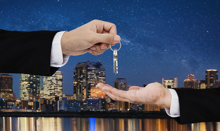 Real estate business, residential rental and investment. Businessman handover keys, with city at night in Japan backgroundsの写真素材