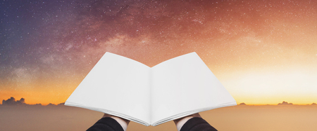 Hand holding opened book, blank pages on colorful starry sky. Concepts of imagination, knowledge, wisdom and educationの写真素材