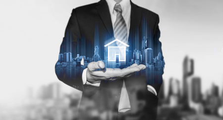 Businessman holding modern buildings hologram, and home icon. Real estate business, building technology and smart home conceptの写真素材