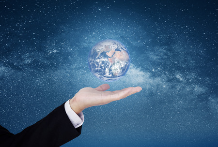 Businessman showing the world on hand, on blue starry space background.の写真素材