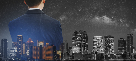Business concept, Businessman in black suit with double exposure panoramic modern city at nightの写真素材