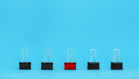Unique, leadership, individuality, and think different concept. Office supplies, red binder paper clip stand out of other clipsの写真素材