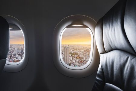 Looking through airplane window with aerial view of Osaka city in Japan and sunlight in sunsetの写真素材
