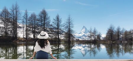 Woman in white hat looking at Matterhorn mountain with lake in Zermatt, Switzerlandの写真素材