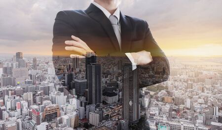 Business leader in black suit with arm crossed, Double exposure city in sunsetの写真素材