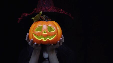 Woman in Halloween costume holding Halloween pumpkin or Jack O Lantern instead of headの写真素材