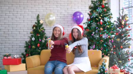 Blurred defocused, Asian girls pulling Confetti party popper in Christmas partyの写真素材
