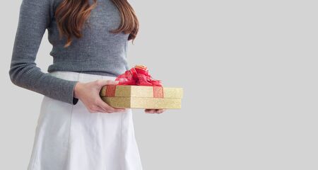 Young woman holding gift box, on gray backgroundの写真素材
