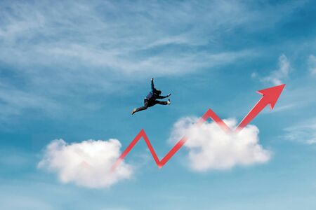 Success, achievement and business growth concepts. a man jumping over clouds with raising arrowの写真素材