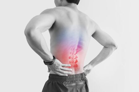 Lower back pain. Shirtless man touching his back with red highlight, on white backgroundの写真素材