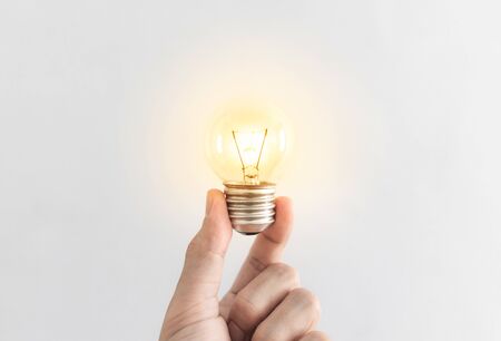 Hand holding glowing light bulb. New ideas, innovation and inspiration conceptの写真素材
