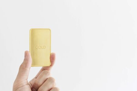 Hand holding 96.5 percent gold bar, isolated on white backgroundの写真素材