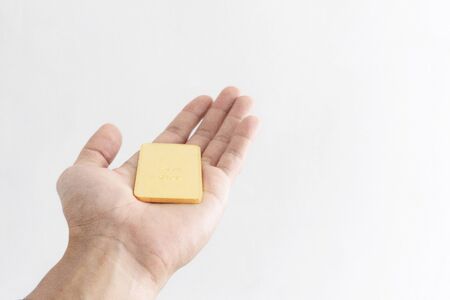 Hand holding 96.5 percent gold bar, isolated on white background