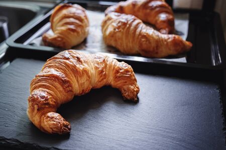 Fresh baked Croissants on black stone plate, and black trayの写真素材