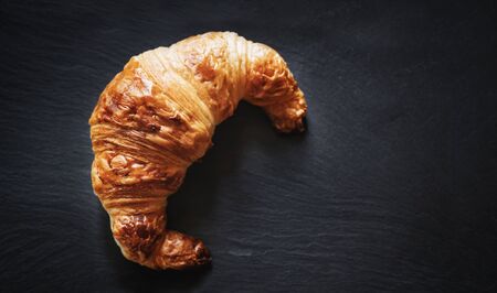 Fresh French Croissant on black stone plate texture backgroundの写真素材