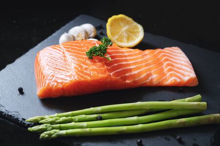Fresh raw Salmon slice with herb and ingredients, on black slate plateの写真素材