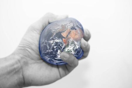 Hand squeezing the world. World crisis, saving earth concept.の写真素材