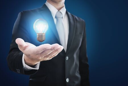 Businessman holding glowing light bulb on hand. New ideas, innovation and inspiration conceptの写真素材