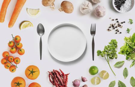 Healthy and Vegetarian Eating Concept. White dish surround with organic vegetables, herbs and spices, on white backgroundの写真素材