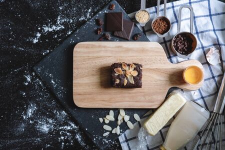 Chocolate brownie on wooden plate, surround with ingredients. Homemade dessert and bakeryの写真素材