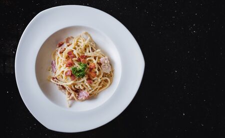 Spaghetti Carbonara in white dish, on black stone table with copy spaceの写真素材