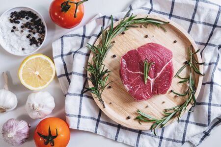 Raw beef steak Tenderloin fillet, with tomatoes, Rosemary and lemon, on wooden boardの写真素材